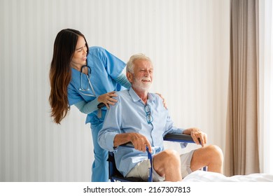 Friendly Staff Caregiver Of Nursing Home Talking To Elderly Man On Wheelchair In The Bedroom.