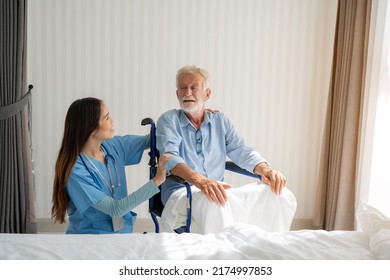 Friendly Staff Caregiver Of Nursing Home Talking To Elderly Man On Wheelchair In The Bedroom.