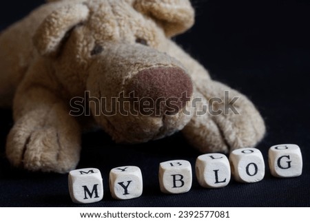 Friendly stuffed toy dog next to the inscription my blog. Design concept of a website-blog or an Internet page for a pet. Black background. Photo. Selective focusing. Close-up
