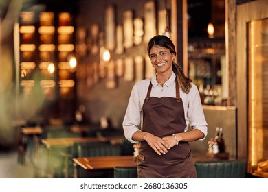 Friendly waitress posing in a warmly lit, stylish restaurant with cozy ambiance.