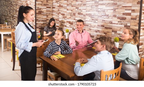 Friendly waitress taking order from guests and writing into note - Powered by Shutterstock