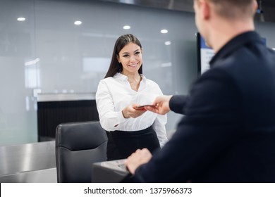 Friendly Woman Staff Taking Passport From Passenger At Airport Check In Desk