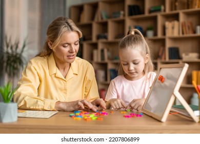 Friendly Woman Teaching Pretty Little Girl Alphabet, Specialist Working With Child, Making Words From Colorful Plastic Letters Together At Child Development Classes