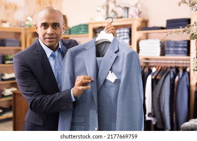 Friendly Young Adult Male Seller Suggesting Suit In Clothing Store