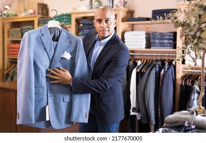 Friendly Young Adult Male Seller Suggesting Suit In Clothing Store