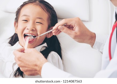 Friendly Young Dentist Examining Happy Child Teeth In Dental Clinic. Dentistry Concept.