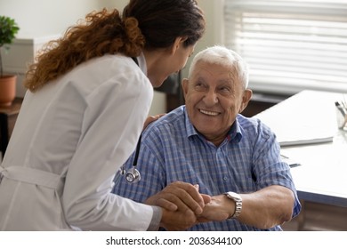 Friendly young female doctor and optimistic elder 80s man meeting in office for consultation. GP therapist holding hands of old patient, giving sympathy, support, advice about treatment - Shutterstock ID 2036344100