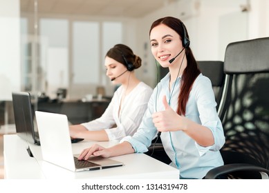 Friendly Young Female Technical Support Dispatcher With A Headset Working In A Call Center On A Hotline, Talking On The Phone. Portrait Of An Attractive Customer Care Representative