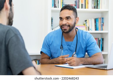 Friendly Young Hispanic Doctor Or Nurse Talking With Patient At Office Of Hospital