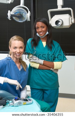 Friendly young multi ethnic personnel group graduated dentist and assistant Caucasian blond and African-American are smiling at dental office