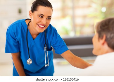 friendly young nurse talking to senior patient in hospital