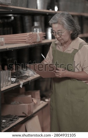 A friendly young retail worker recommends handmade bowls to a customer near rustic warehouse shelving in a warm local pottery shop under warm ambient store lighting.