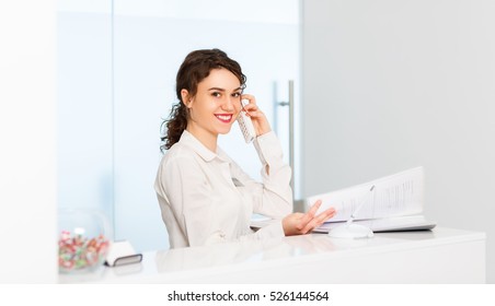 Friendly Young Woman Behind The Reception Desk Administrator