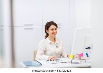 Friendly Young Woman Behind The Reception Desk Administrator