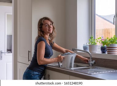 Friendly Young Woman Filling The Kettle To Make A Hot Drink