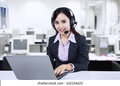 Friendly young woman operator with headset at modern office