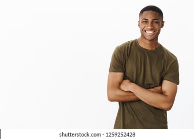Friendly-looking delighted self-assured handsome african-american male cross arms aganst chest and smiling as having ambitiouns and determined to follow own dreams over white background