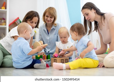 Friends with babies toddlers playing on the floor in sitting room or nursery