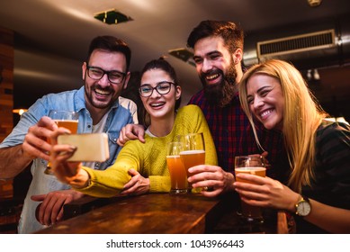 Friends At The Bar Drinking Beer Looking Into Smartphone 