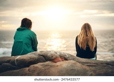 Friends, beach and sunset of people sitting on rock for bonding, holiday in Ireland or back view. Vacation, travel and relax for fun day by ocean, nature or contemplation in outdoors for togetherness - Powered by Shutterstock