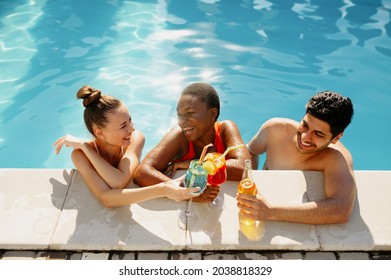 Friends with beverages pose at the edge of pool - Powered by Shutterstock