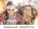 Friends blowing confetti in Carnival Festival. Woman in street party, blur and abstract