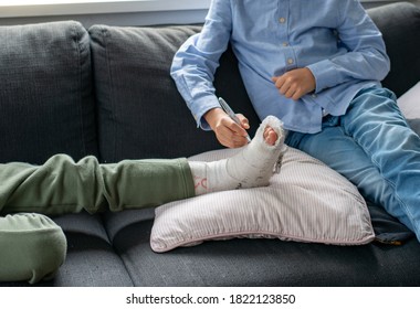 Friends, A Boy Playing Writing On The Plaster Cast Of The Broken Leg Of The Friend Accident.