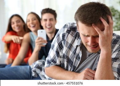 Friends bullying to a sad boy and taking photos with a smartphone for the social network - Powered by Shutterstock