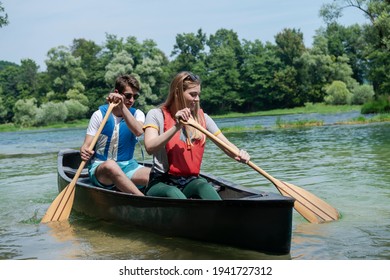 Friends Are Canoeing In A Wild River