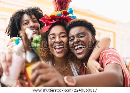 Friends celebrating Carnival in the street. Brazilian people toasting and smiling together.