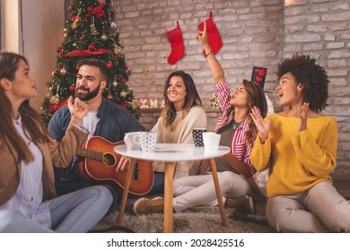 Friends Celebrating Christmas At Home, Eating Christmas Cookies, Drinking Coffee, Playing The Guitar And Singing Christmas Songs