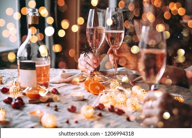 Friends celebrating Christmas or New Year eve. Party table with rose champagne.