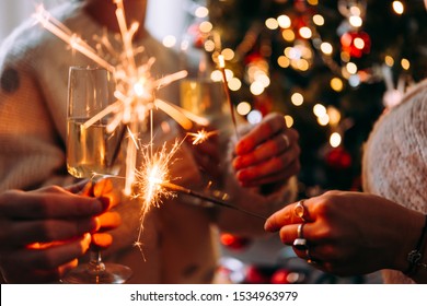 Friends celebrating Christmas or New Year eve party with Bengal lights and champagne.