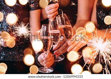Friends celebrating Christmas or New Year eve party with Bengal lights and rose champagne.
