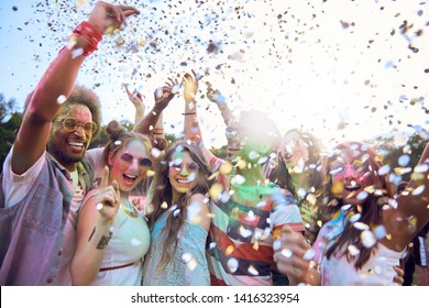 Freunde feiern Holi-Festival unter Dusche von Konfetti
