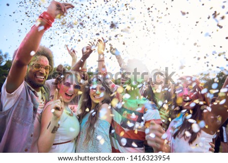 Friends celebrating holi festival under shower of confetti
