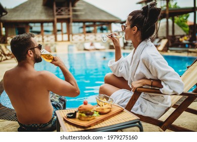 Friends cheering each other in luxury resort by the swimming pool stock photo. Drinking alcohol photos. - Powered by Shutterstock