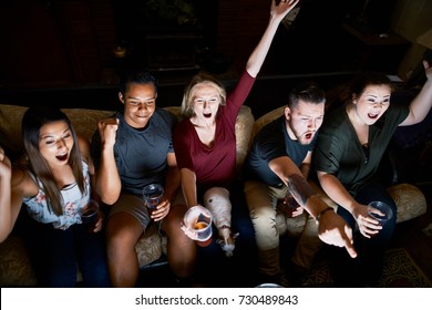 Friends Cheering While Watching Game On Tv At Night