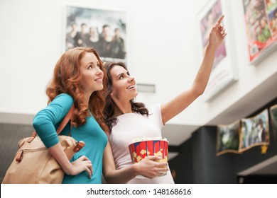 Friends choosing movie at the cinema. Beautiful young female friends choosing movie to see at the cinema - Powered by Shutterstock