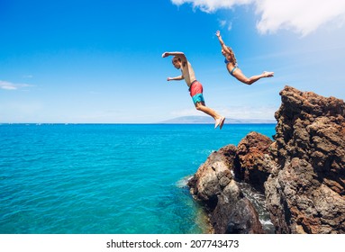 Friends cliff jumping into the ocean, summer fun lifestyle.