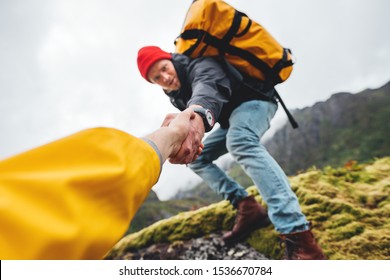 Friends Climb To Mountains And Help Together Lifestyle Outdoor Vacation. POV View On Brave Tourist Helping His Active Friend Holding To Hand Climbing To Rock