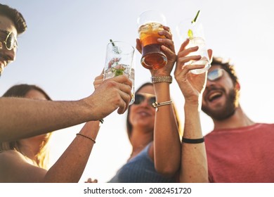 Friends clinking alcoholic cocktail glasses together - Carefree young people in summer drinking and toasting of friendship. Shallow DOF with focus on the left one glass - Powered by Shutterstock