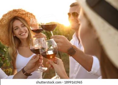 Friends clinking glasses of red wine at vineyard on sunny day, closeup - Powered by Shutterstock