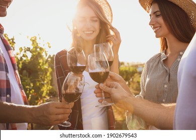 Friends clinking glasses of red wine at vineyard on sunny day, closeup - Powered by Shutterstock