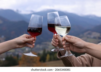 Friends clinking glasses of wine in mountains, closeup