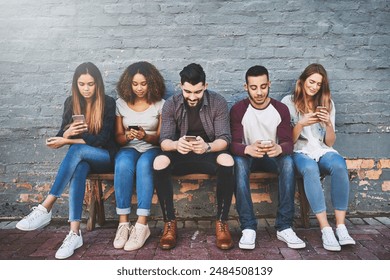 Friends, connection and outdoor with phone for social network, support and communication by brick wall. Group of people, internet and community with technology for diversity, online and networking - Powered by Shutterstock