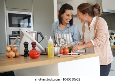 Friends cooking together with kitchen robot and tablet