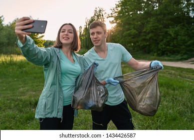 Friends Crouching With Bag Picking Up Trash Doing Plogging.Plogging Concept. Boy And Girl Picking Up Trash From The Forest. They Collecting The Litter In Garbage Bag