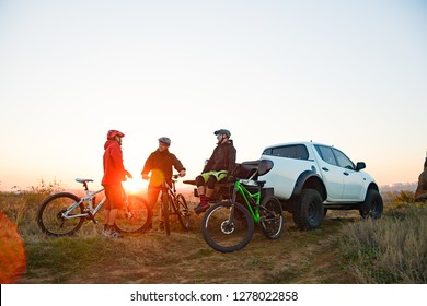 Friends Cyclists Resting near the Pickup Off Road Truck after Enduro Bike Riding in the Mountains at Warm Autumn Sunset. MTB Adventure and Car Travel Concept. - Powered by Shutterstock