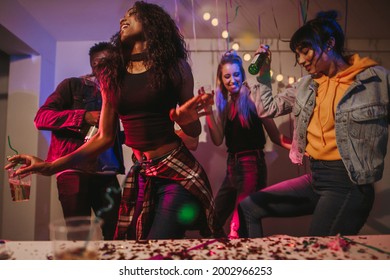 Friends dancing holding drinks at house party. Young women enjoying and having fun at the house party.